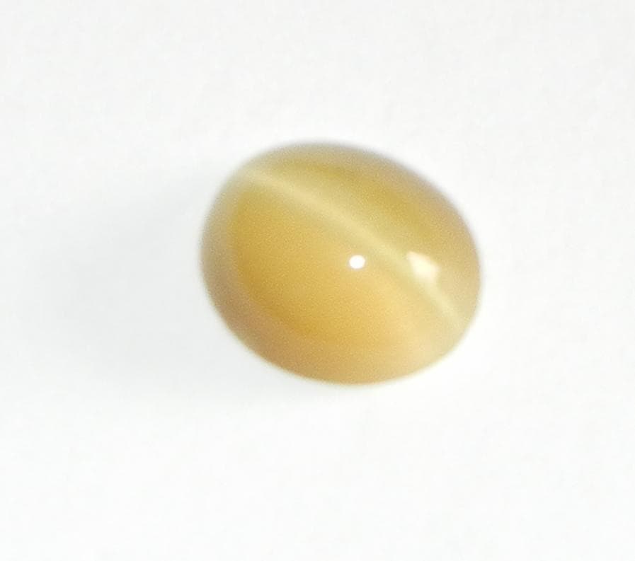 Honey-yellow cat's eye quartz cabochon with a bright chatoyant band