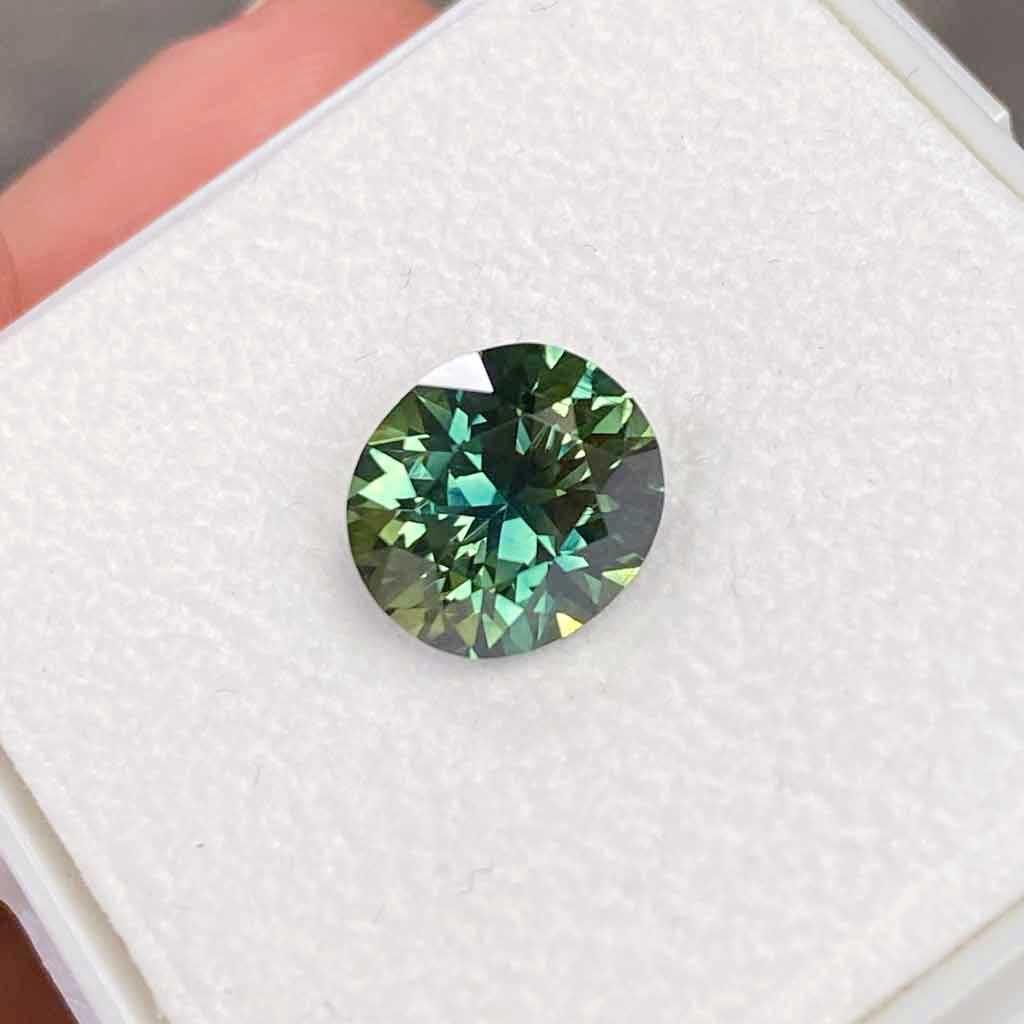Faceted teal-green Australian sapphire in a gem box