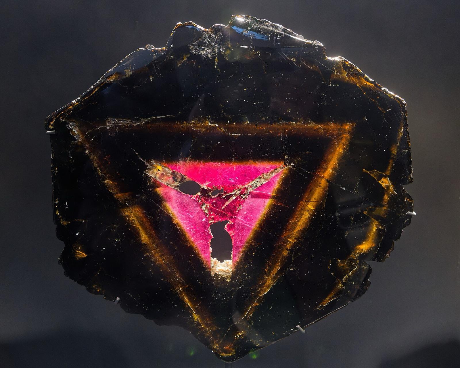 Polished liddicoatite slice with a pink triangular core inside dark zones, Anjanabonoina, Madagascar