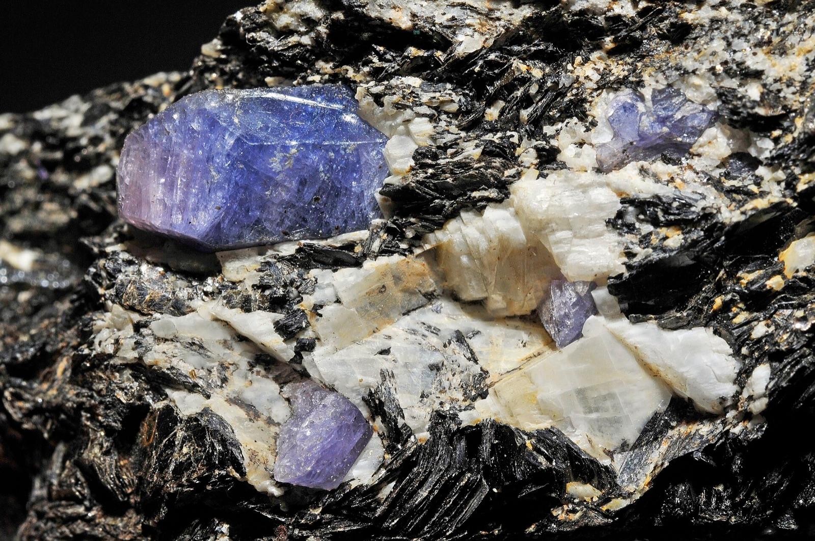 Several violet-blue sapphire crystals in biotite and feldspar, Zazafotsy quarry, Madagascar