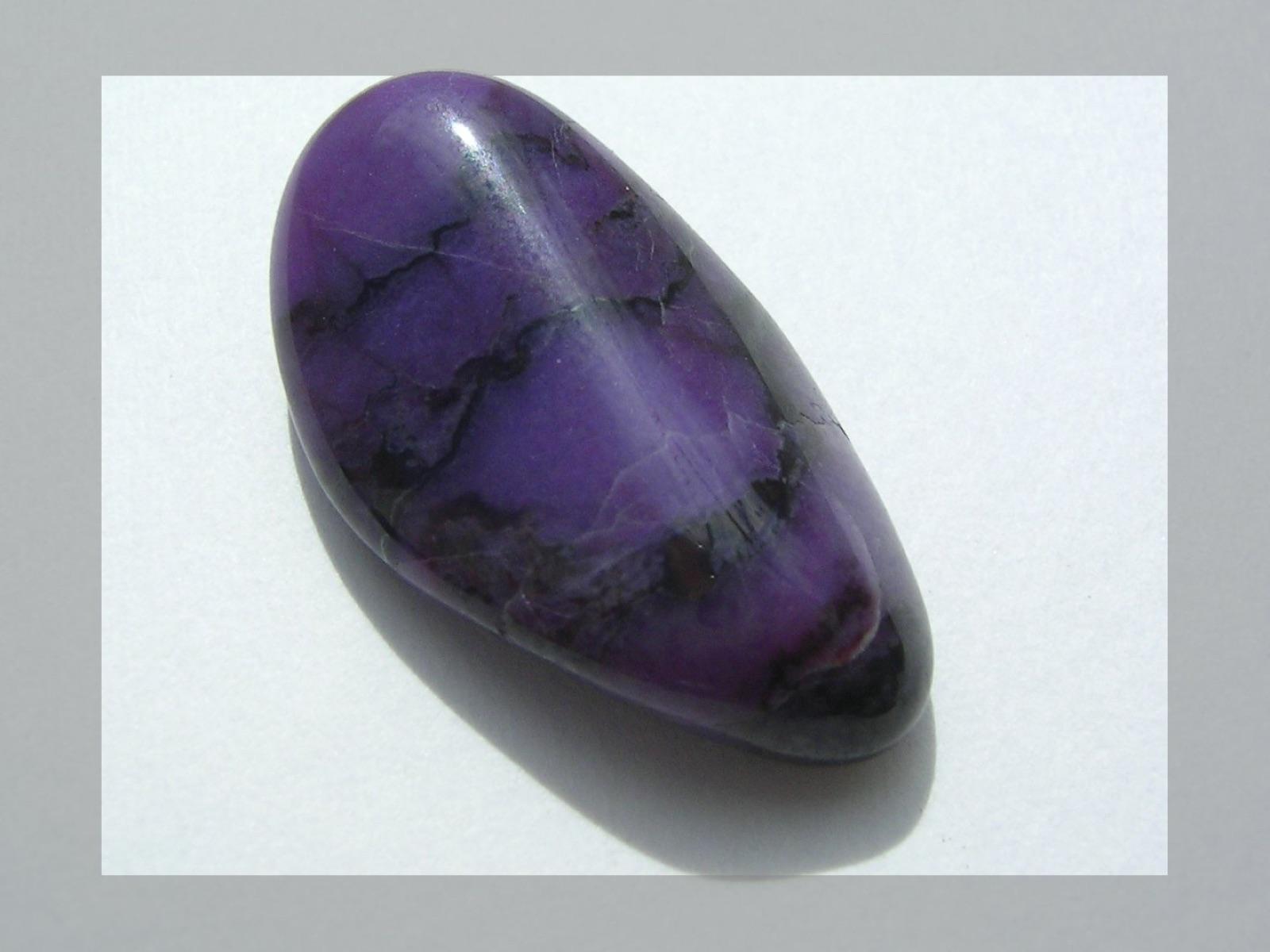 Polished purple sugilite cabochon with dark veining