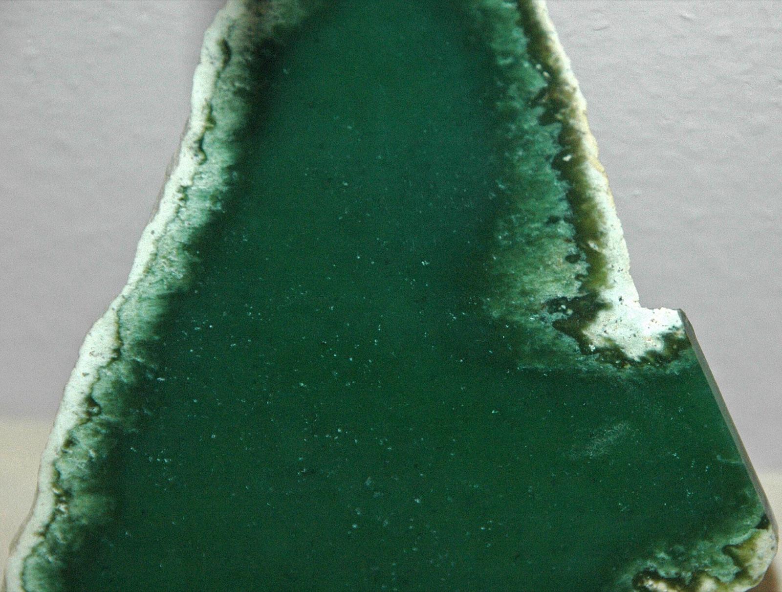 Polished slice of dark green Wyoming nephrite jade with a pale rind